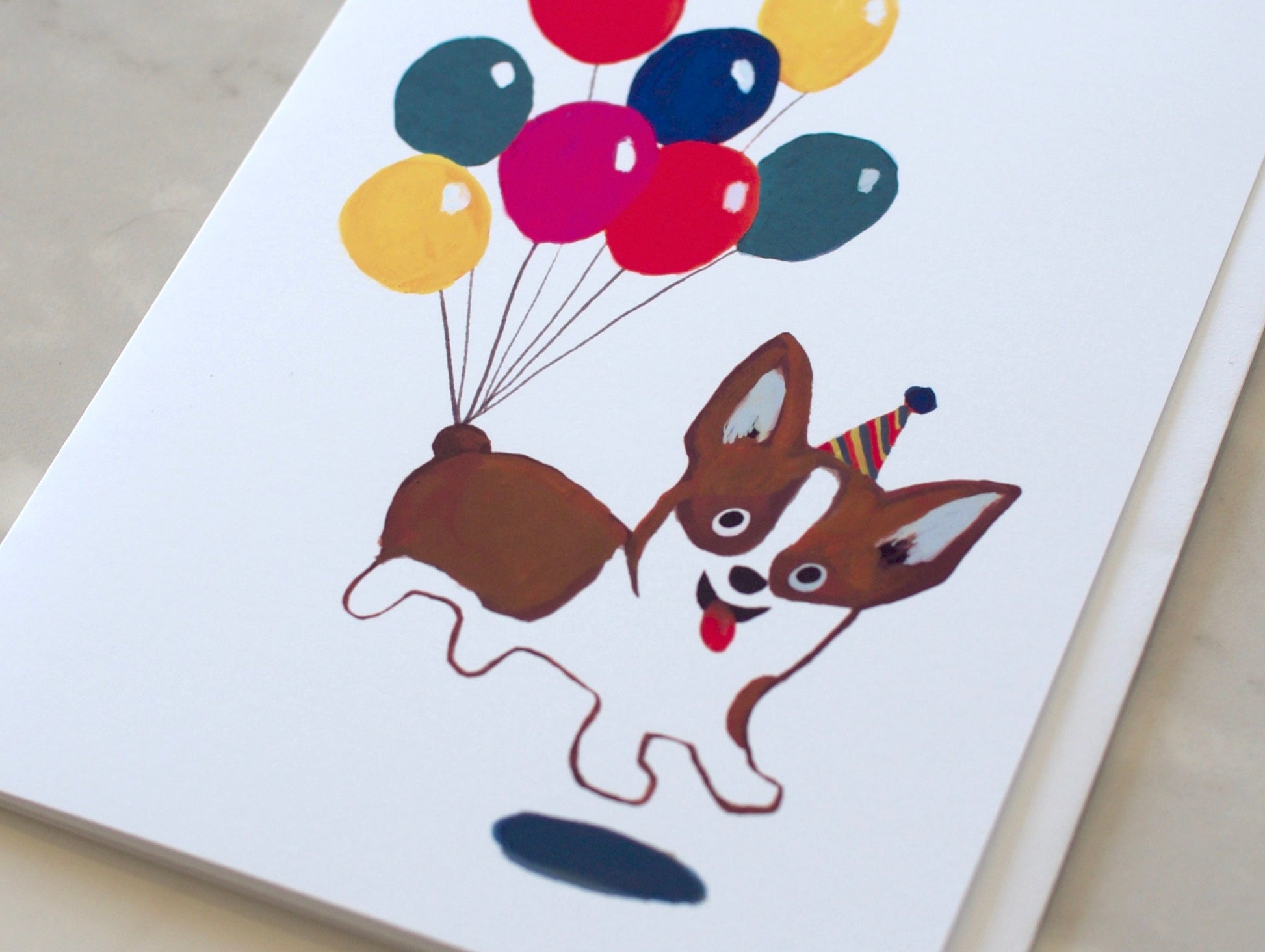 Card with a corgi floating on balloons on a marble background