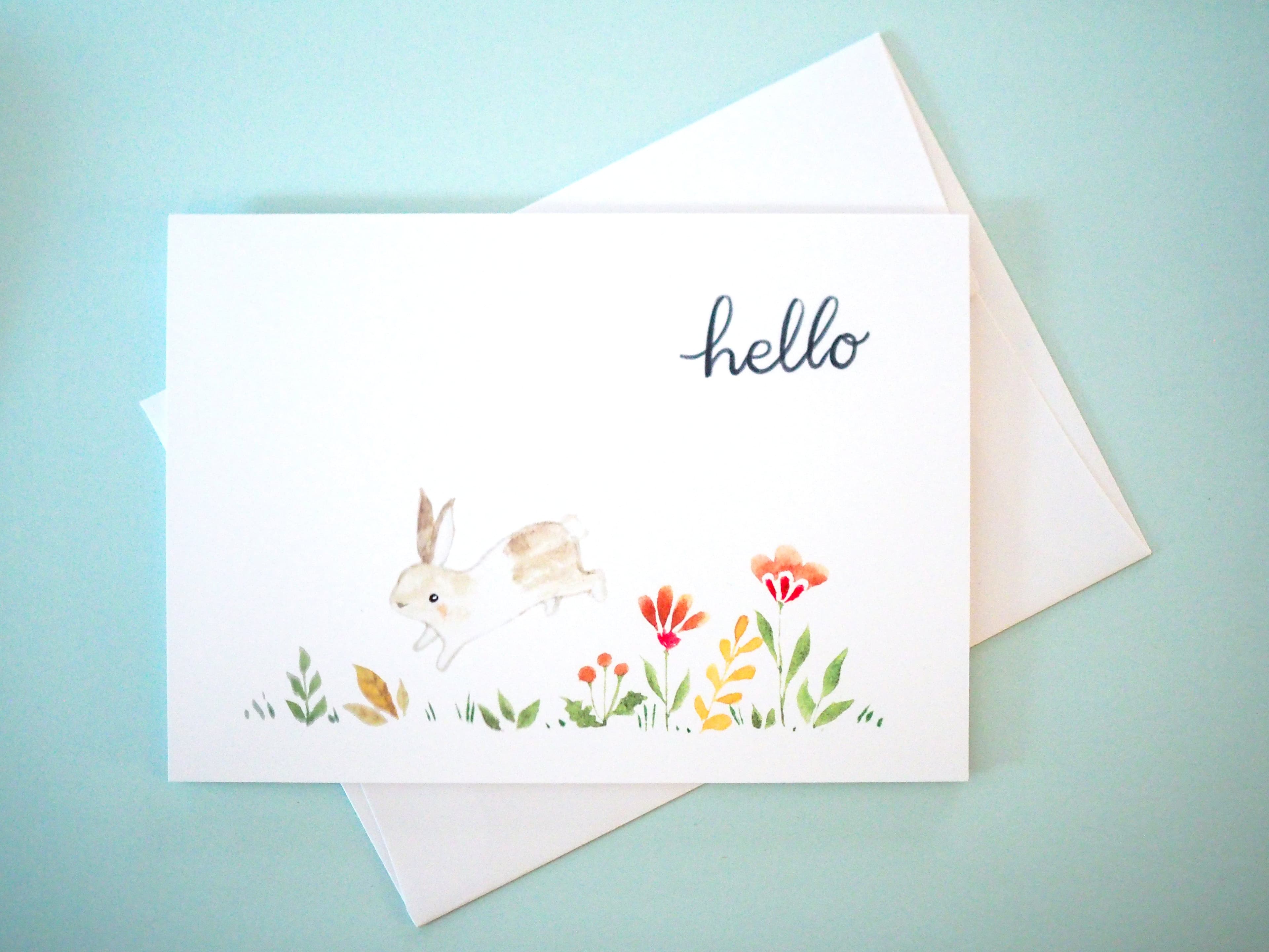 Greeting card with rabbits and flowers on a light blue background