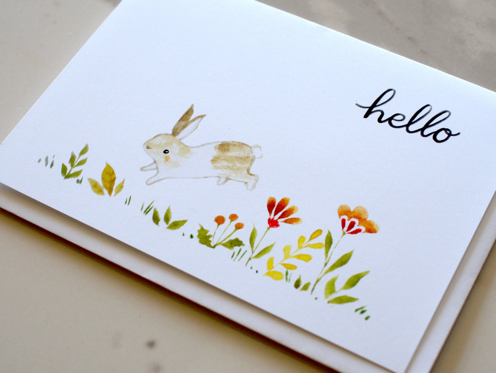 Greeting card with a rabbit illustration and 'hello' text on a neutral background