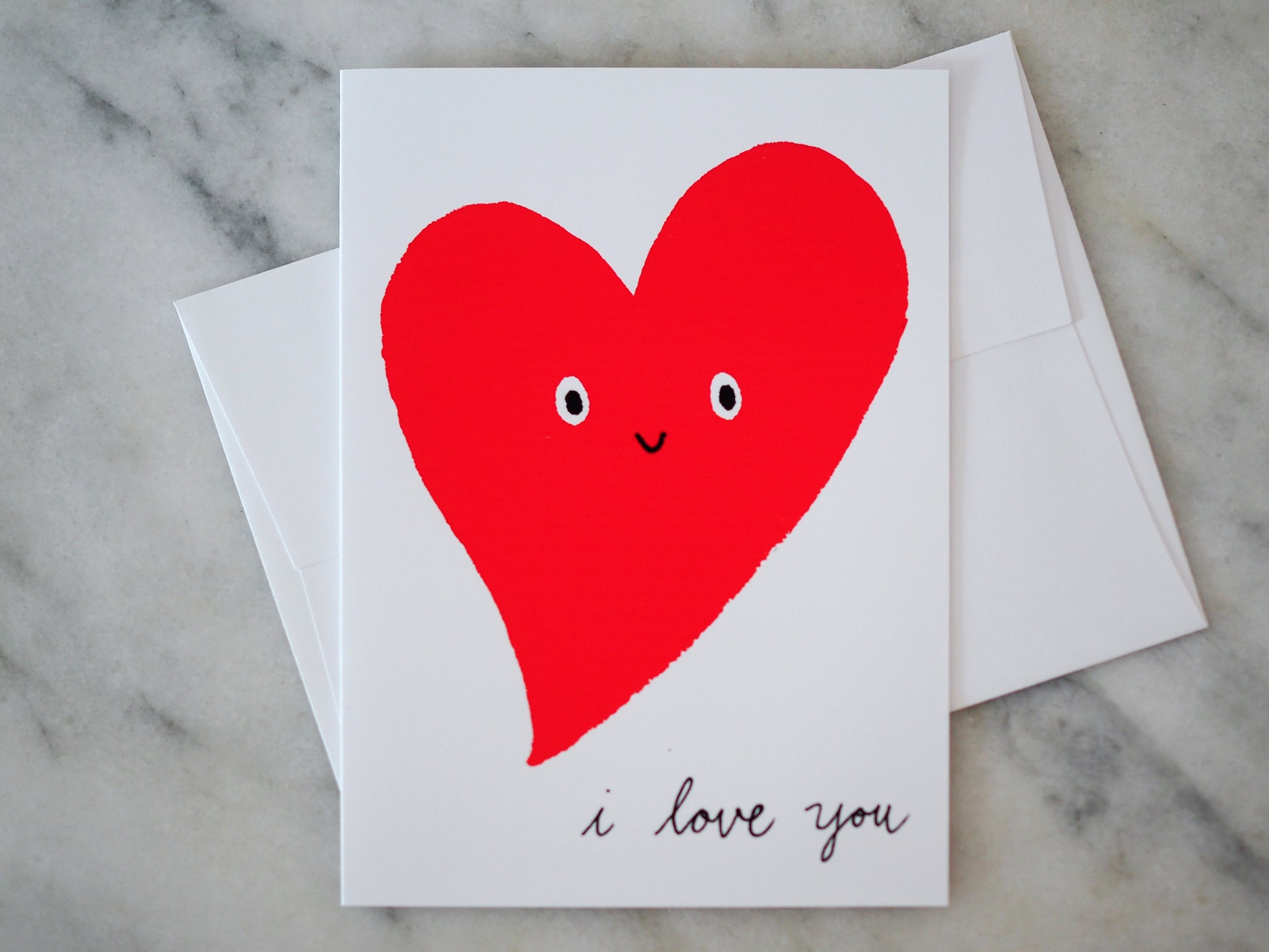 Card with a red heart and 'I love you' text on a marble surface
