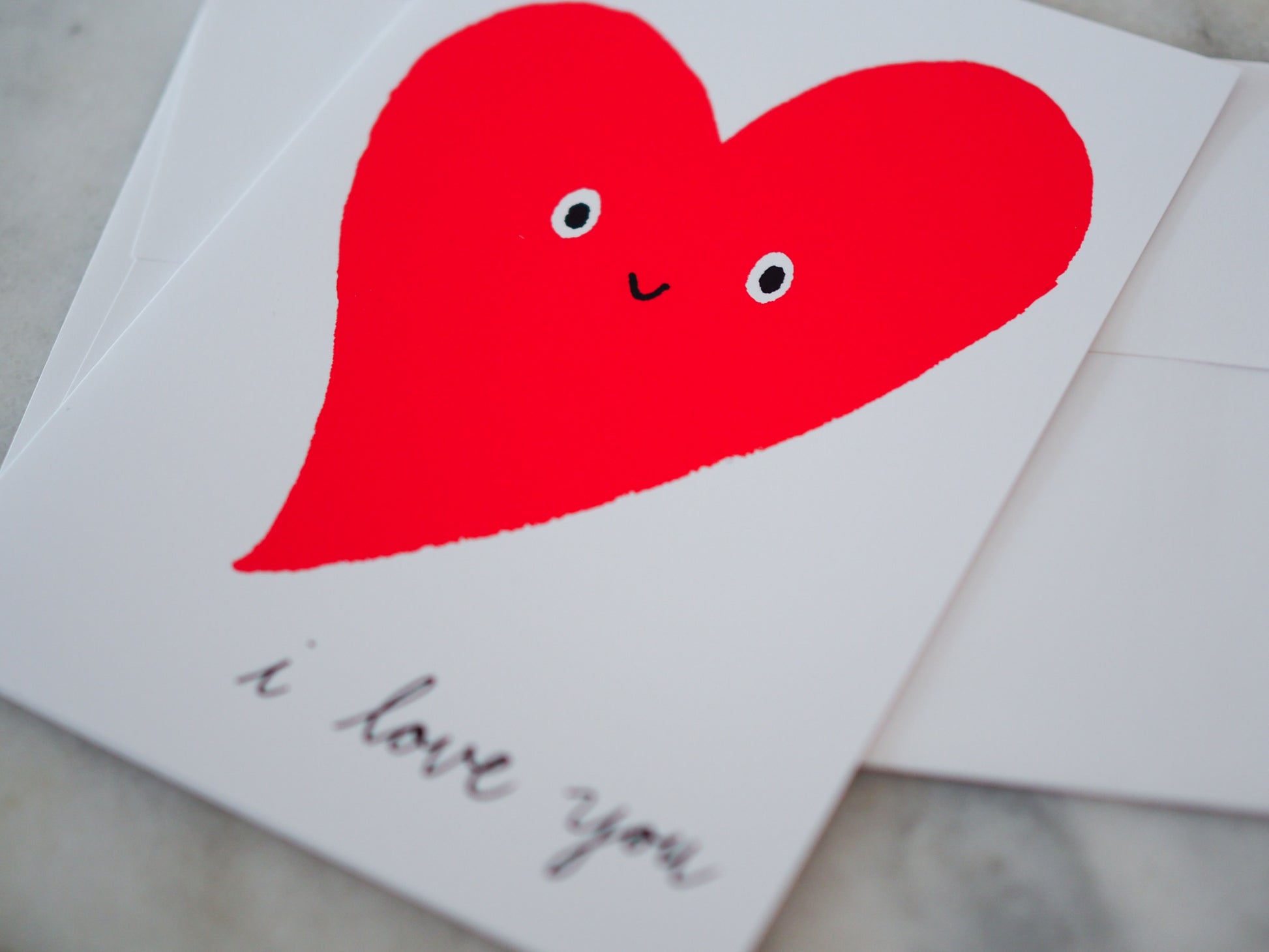 Card with a red heart with eyes and a smiley face on a white background