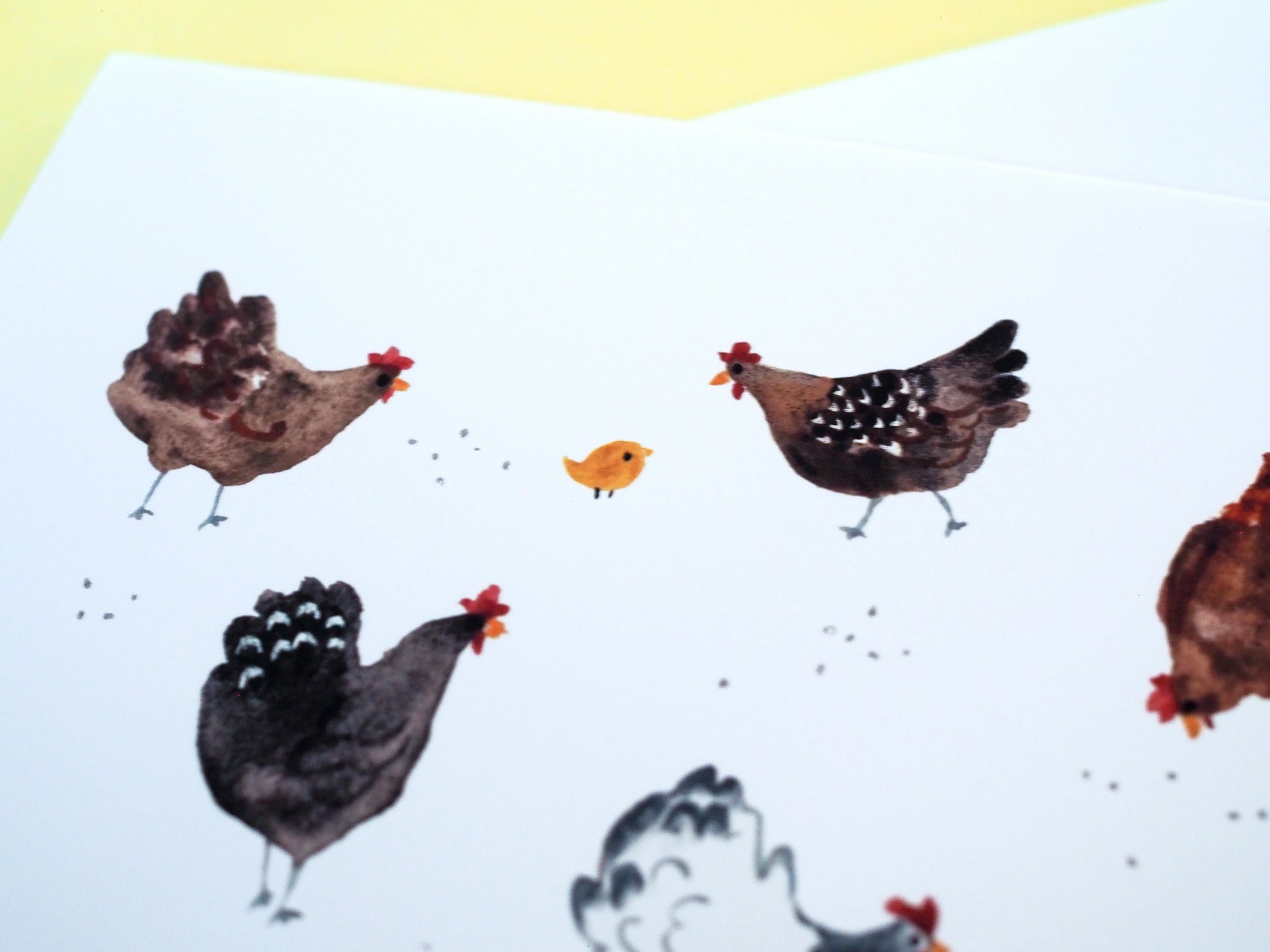 A greeting card detail photo featuring an illustration of various chickens and small chicks on the ground.